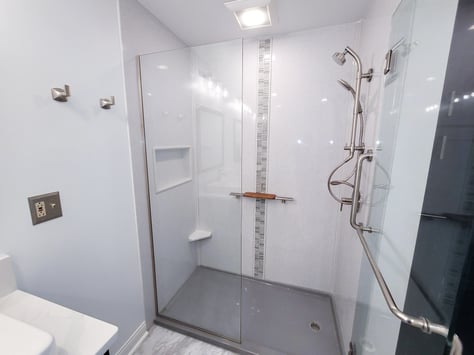 Light Onyx shower walls with a dark base and complimentary, vertical accent strip